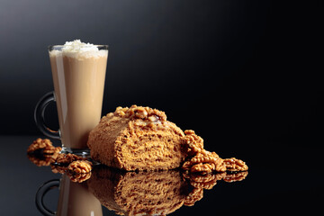 Walnut cake and coffee latte with cream on a reflective background.