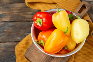 Sweet pepper. Red and yellow and orange peppers in a metal bowl on a brown wooden table. Pepper close-up