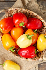 Sweet pepper. Red, yellow and orange peppers in a basket on a brown wooden table. Paprika close-up	