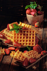 Waffles with strawberries and mint twig.