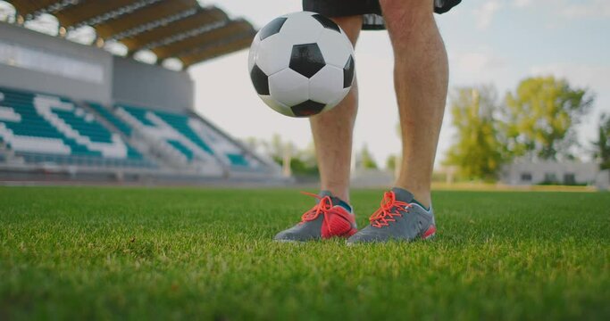 A man on a football field in slow motion in sports equipment bounce a soccer ball