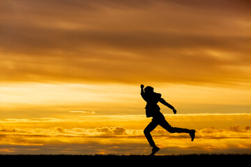 夕陽を背景に元気よく走る男性のシルエット