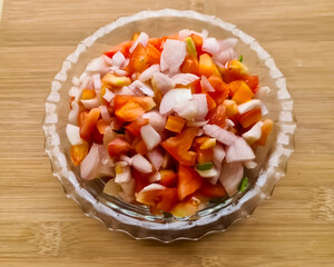 Selective focus on chopped tomatoes and onions in glass bowl 