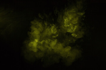 Colorful smoke close-up on a black background. Yellow cloud of smoke.
