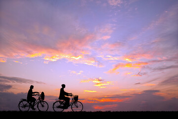 Fototapeta na wymiar 夕陽を背景に自転車通学する男女のシルエット