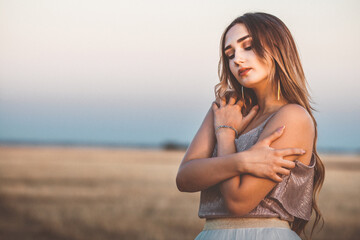 Fototapeta premium Happy woman on hay stack walking in evening, beautiful romantic girl with long hair outdoors lean on bale in field