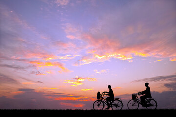 夕陽を背景に自転車通学する男女のシルエット