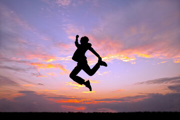 Fototapeta na wymiar 夕陽を背景に元気よくジャンプする男性の横姿シルエット