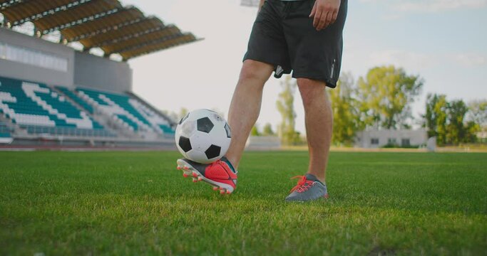 A male footballer juggles kicking a soccer ball in a slow-motion close-up. To stuff the ball. 