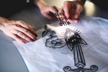 Cropped view of designers working with sketches on stencils for screen printing  