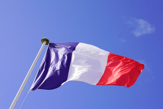 Flag of France waving in the wind on clear blue sky
