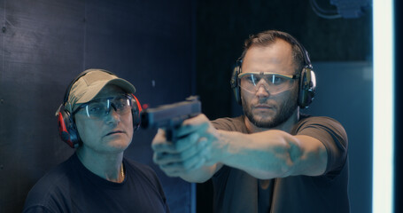 Mature instructor teaching man to shoot pistol