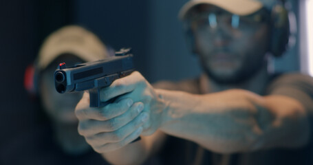 Middle aged shooter firing pistol - obrazy, fototapety, plakaty