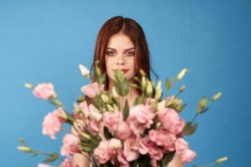 Obraz na płótnie Canvas Beautiful woman with a bouquet of pink flowers on a blue background spring model 