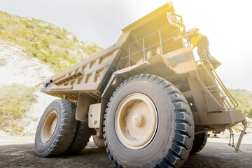 Driver walks up a large mining dump truck.
