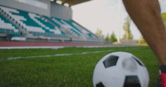 Close up of a male soccer player running with a soccer ball on the football field in the stadium demonstrating excellent dribbling