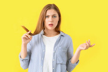 Stressed woman with hair problem on color background