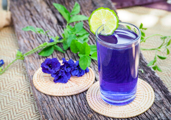 Obraz na płótnie Canvas Fresh purple Butterfly pea or blue pea flower and juice in glass with lime on wooden table. 