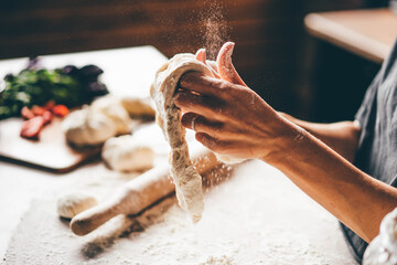 Woman kneading dough.. Young woman prepare dough on special kitchen table at home close view