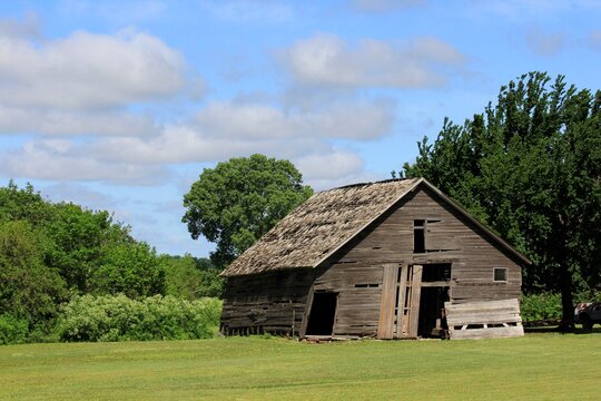 old barn in the countryside with blue sky and white clouds.
