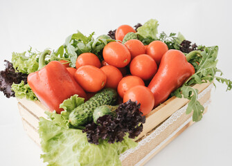 Closeup of fresh vegetables in the wooden box on white background.