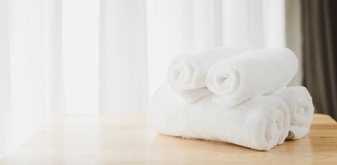 Obraz na płótnie Canvas White soft towels folded on wood table with blurred white bathroom background