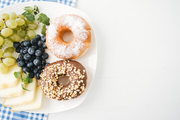 Top view of doughnuts and fresh fruits on the table for breakfast.