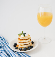 Closeup of pancakes with blueberries and glass of orange juice.
