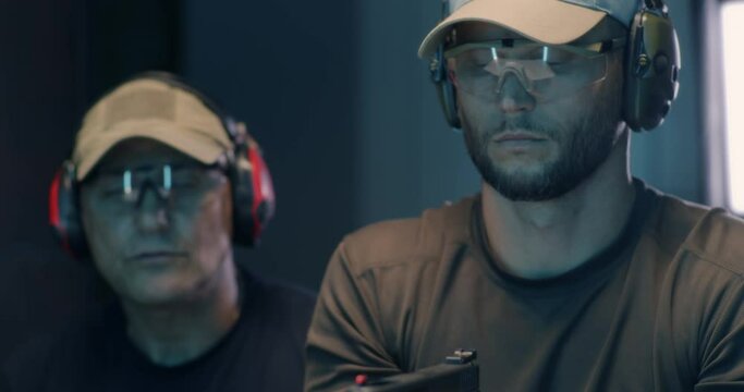 Young man learning to fire pistol with trainer