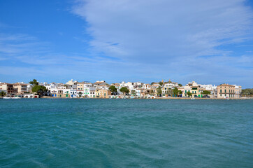 Port of the coastal town Portocolom on Balearic island Mallorca, Spain, panoramic view, colorful traditional houses in the background, turquoise mediterranean sea in front, a sunny day, copy space