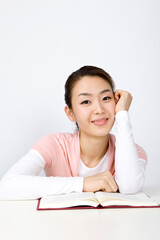 young woman at desk with hand on cheek daydreaming