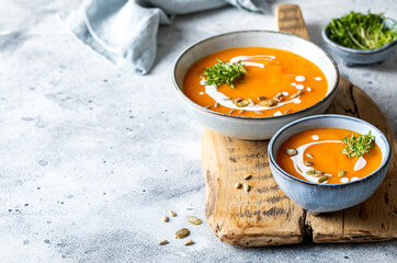 Vegetarian autumn pumpkin and carrot soup with cream, seeds and cilantro micro greens. Comfort...