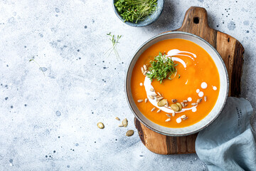 Vegetarian autumn pumpkin and carrot soup with cream, seeds and cilantro micro greens. Comfort food, fall and winter healthy slow food concept