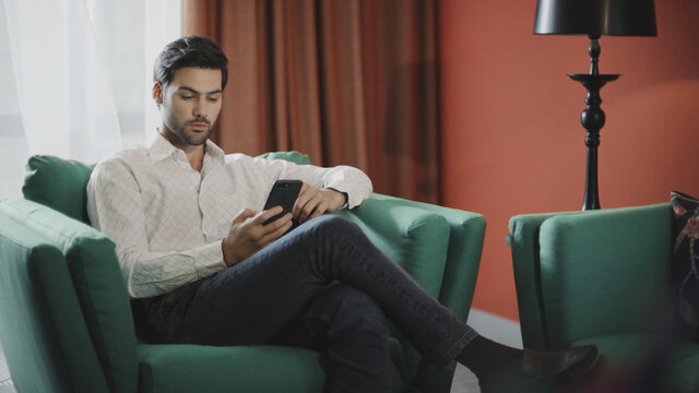 Business man scrolling mobile at luxury hotel. Businessman reading phone