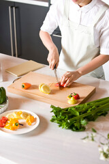 young woman cooking in kitchen with vegetable