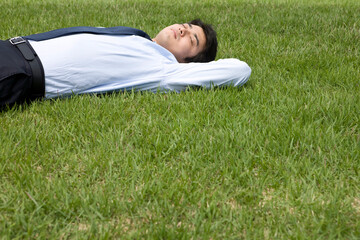 young businessman lying on grass