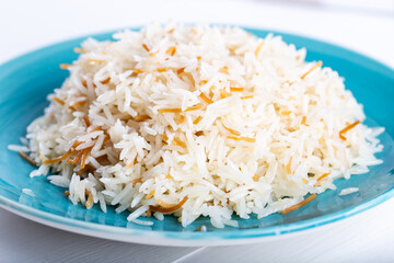 Cooked basmati rice served in a ceramic bowl or plate on white background.