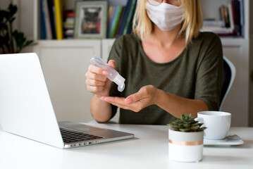Coronavirus. Sanitizer gel. Business woman working at home, use hand sanitizer aganist covid-19. Quarantine. Cleaning hands antibacterial gel. Stay home. Girl learns, using laptop. Freelance. 