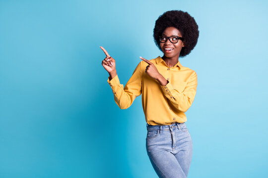 Photo of black skin extensive hairdo girl shiny smile excited directing fingers look empty space suggest zoo opening exposition wear specs yellow shirt jeans isolated blue color background