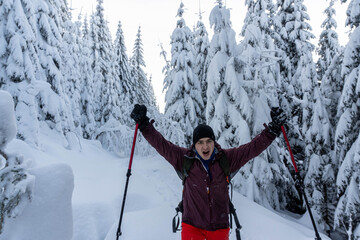 Happy man walking through winter mountain pine forest