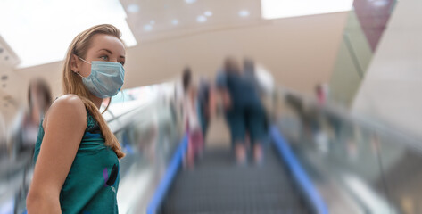 Fototapeta na wymiar Urban city lifestyle. Young beautiful woman with face mask in modern shopping mall.