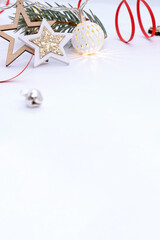 Christmas composition of wooden stars with sparkles, garlands of white luminous balls, fir branches and red ribbons on a white background.