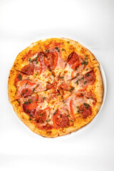 pizza with ham, sausage and tomatoes on a white plate
