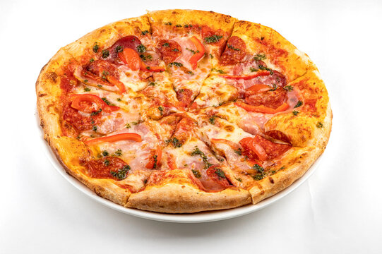 pizza with ham, sausage and tomatoes on a white plate