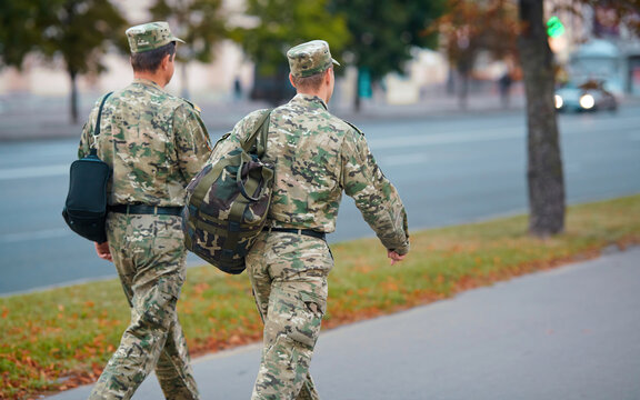 Belarus soldiers in camouflage dress walking through the street in the center of Minsk, with bags behind back, rear view. Group of soldiers. Military men in uniform.
