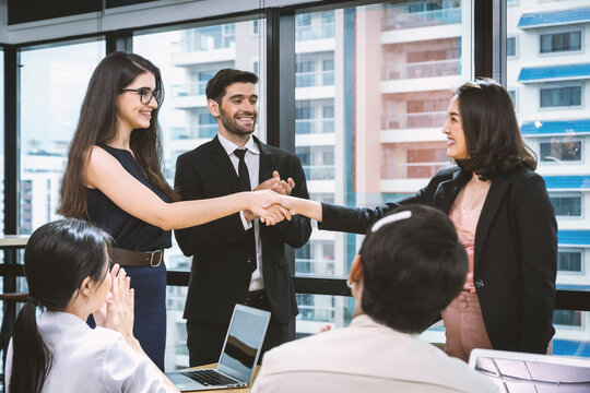Businesswoman shaking hands and smiling with parthner to celebration about contract agreement.