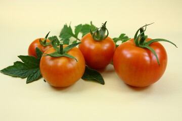 Nahaufnahme von reifen Tomaten mit grünem Blatt auf gelbem Hintergrund bei Kunstlicht