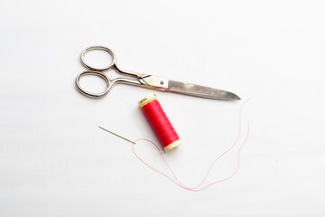 Set of several spools of thread of different colors, a pair of scissors and a tailors tape on a white background.