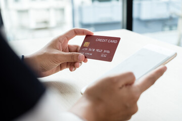 The businesswoman's hand is holding a credit card and using a smartphone for online shopping and internet payment in the office