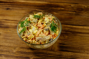 Tasty salad with chicken breast, roasted mushrooms, carrots, grated cheese, eggs and mayonnaise on wooden table